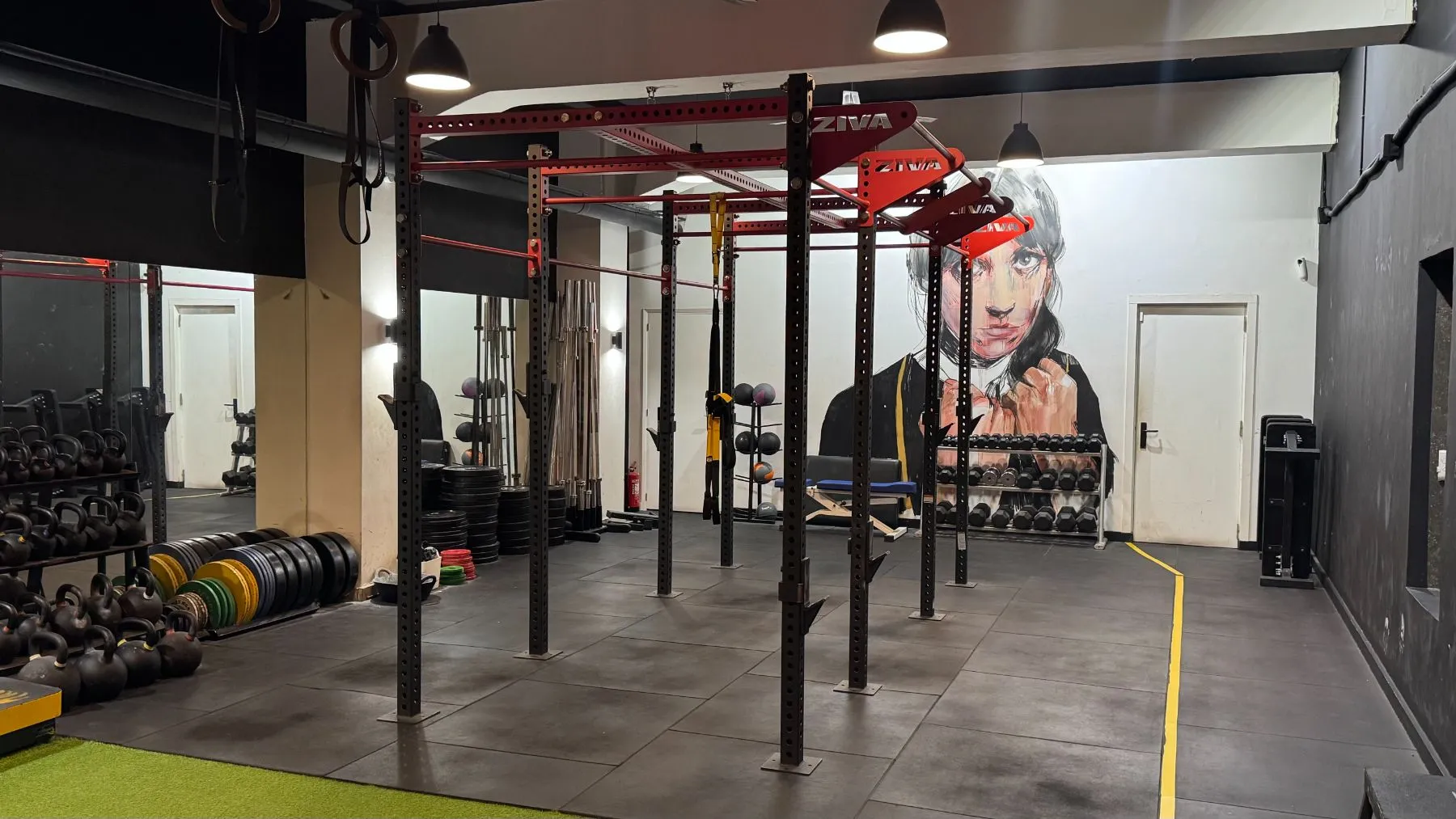 Zona de fuerza con rack, kettlebells, discos y mural